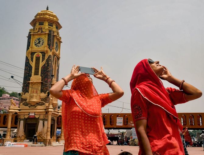 Women look through an X-ray sheet and goggle to get a glimpse of solar eclipse, at Brahma Kund in Har-Ki-Pauri Ganga Ghat, Haridwar, Sunday, June 21, 2020 (PTI Photo)